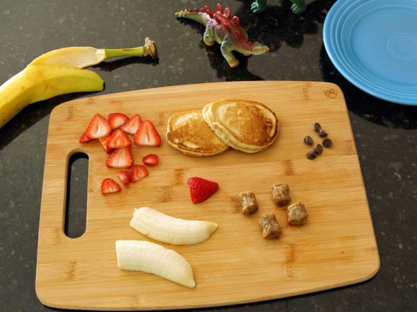 Making a stegosaurus with pancakes, sausage, and fruit
