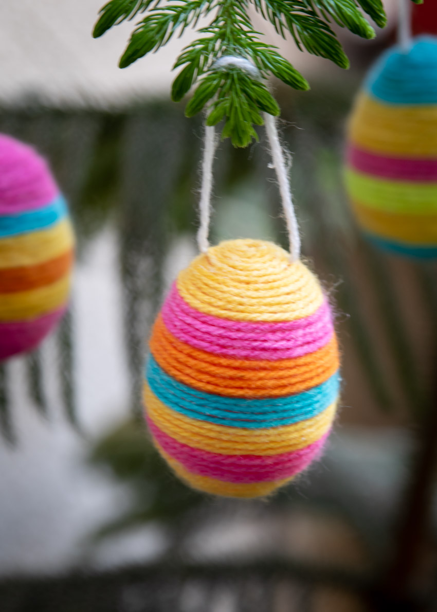 Brighten up your home this Easter with some adorable Hanging Yarn Wrapped Plastic Eggs. It's the perfect holiday craft to make with your kids!