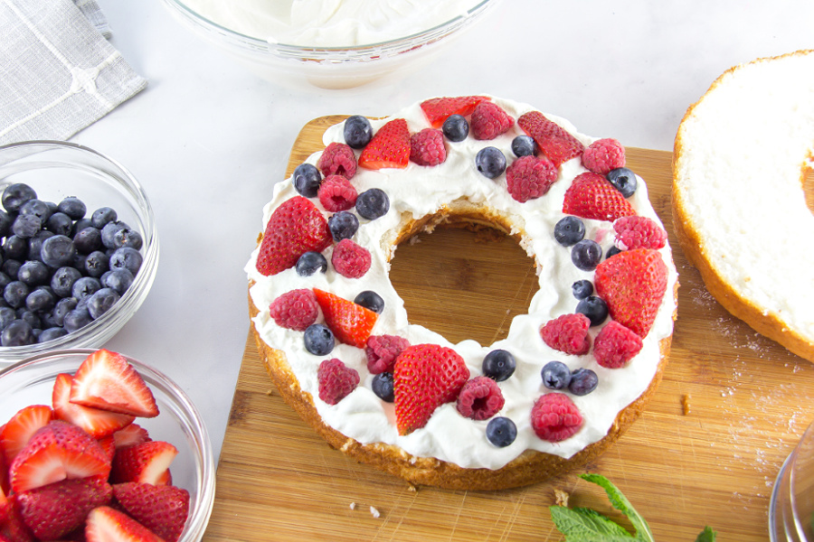 half of an angel food cake topped with whipped cream and fresh berries