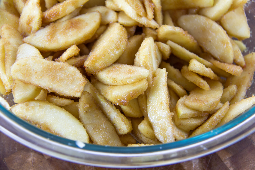 apple slices coated in sugar, herbs, and lemon for making apple pie