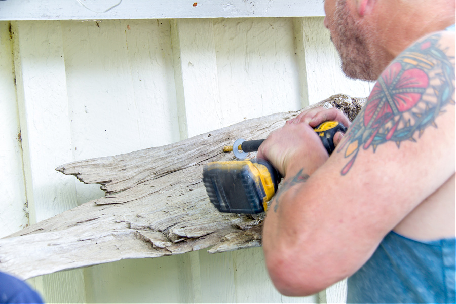 Driftwood being attached to a wall using screws