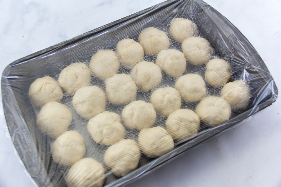 bread dough balls inside a baking dish to make dinner rolls