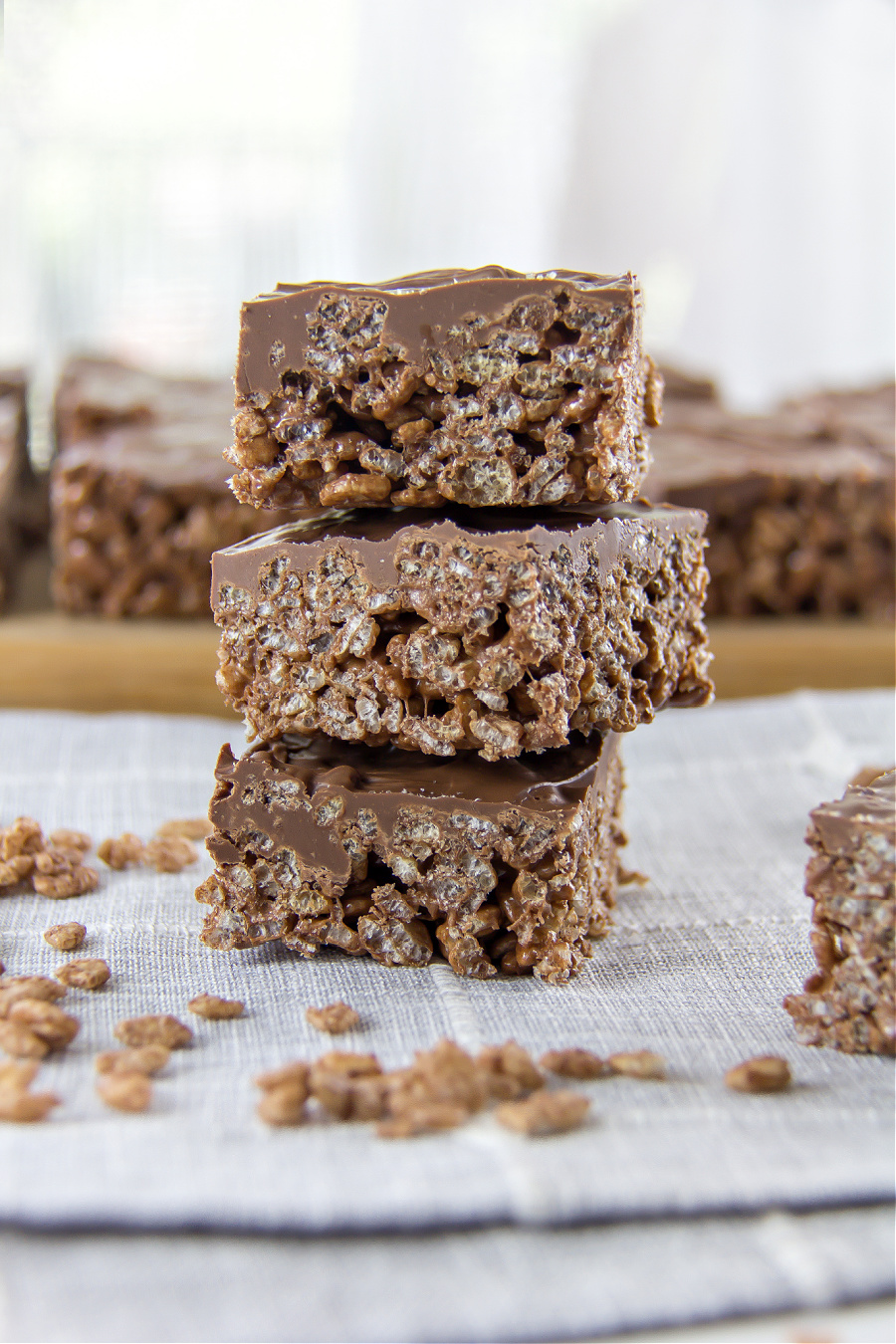 chocolate rice krispies treats stacked on top of a grey tablecloth