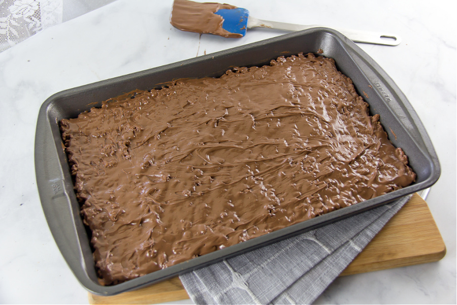 a baking pan with chocolate rice krispies coated in a layer of melted chocolate