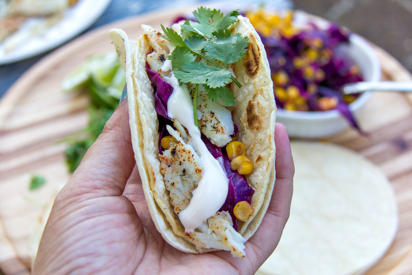 hand holding a fish taco with cabbage slaw