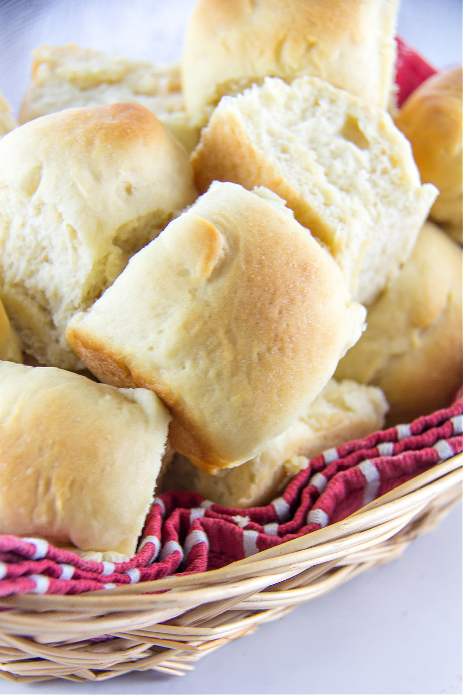 homemade yeast dinner rolls inside a basket with a red towel underneath