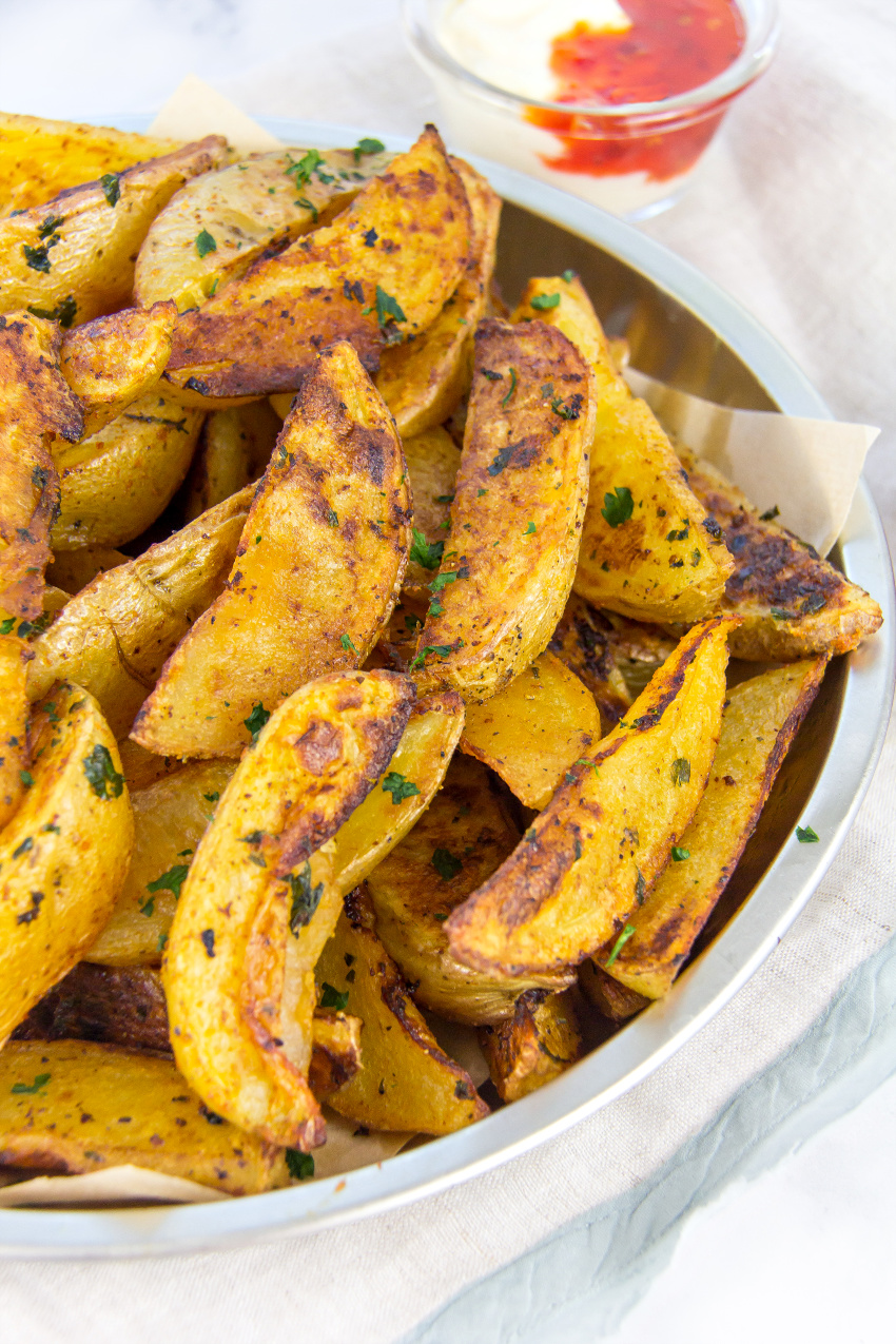 homemade potato wedges on paper in a metal tray