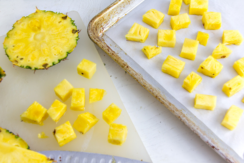 fresh pineapple cut into chunks and placed on a tray for freezing