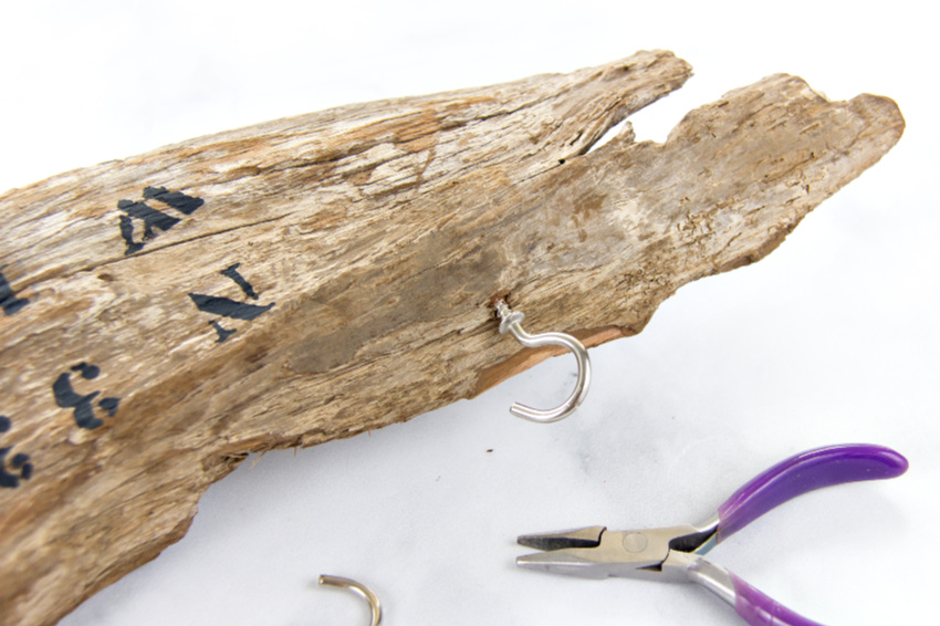 cup hooks being wound into a piece of driftwood