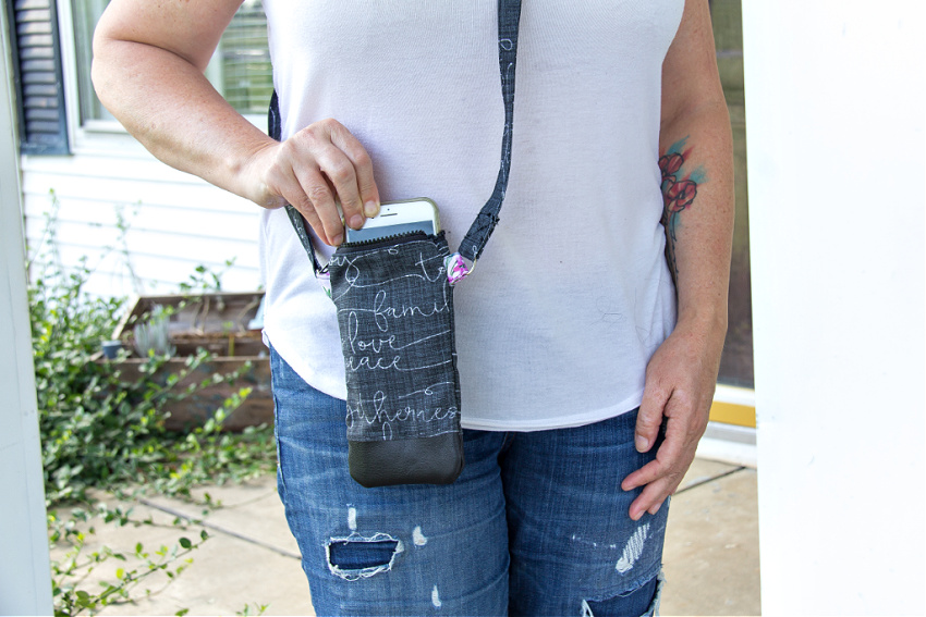 a lady wearing a white t-shirt and jeans with a black cross-body phone purse