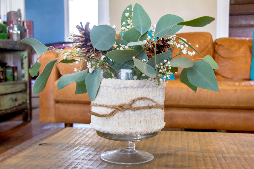 a stand vase with a knit cozy and winter arrangment