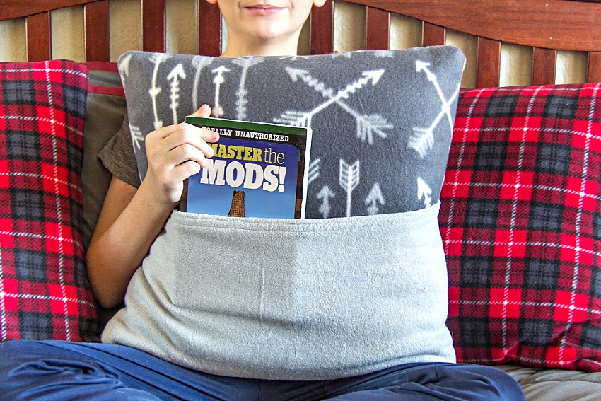 a boy holding a grey fleece book pillow