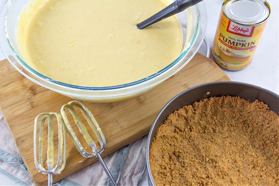 pumpkin cheesecake mix in a bowl and gluten free crust in a pan