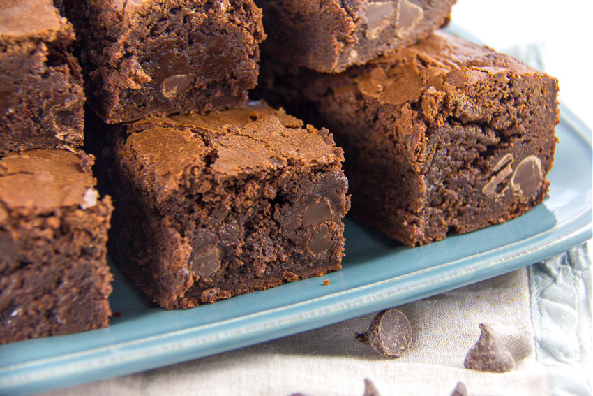 thicky fudgy brownies stacked on a blue tray