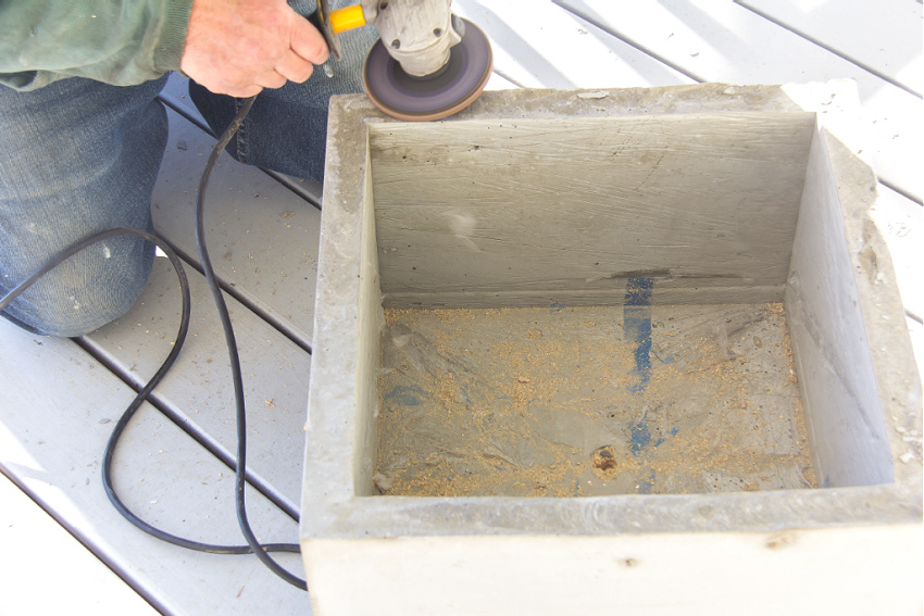 a concrete planter being sanded to make the top smooth