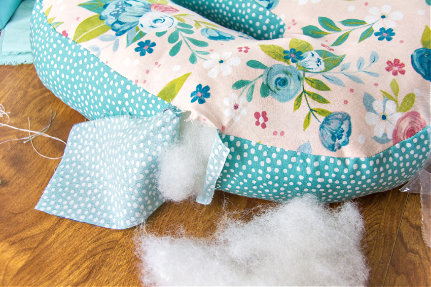 a handmade floral pillow being stuffed with polyfil