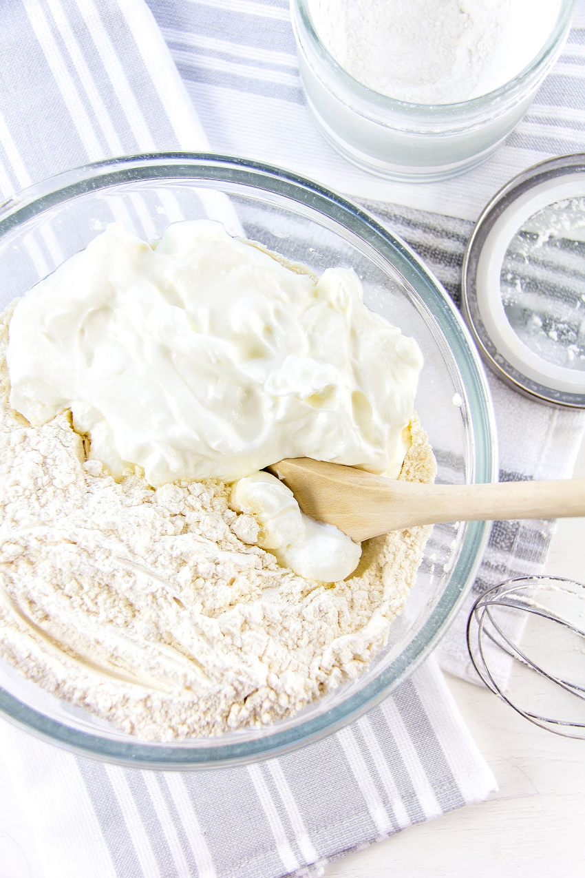 Greek yogurt and flour in a glass bowl with a wooden spoon