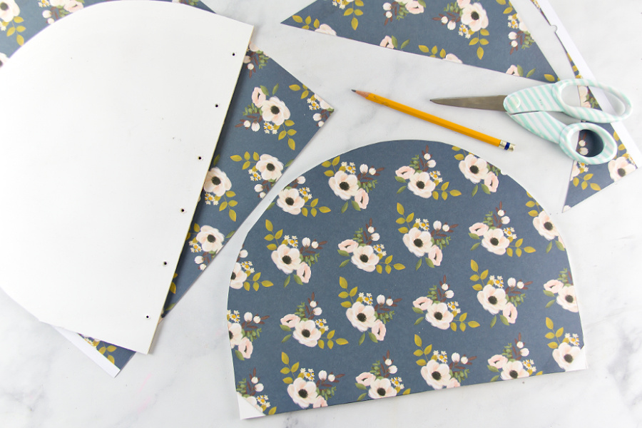 a vintage floral paper being applied to a wood basket lid using mod podge