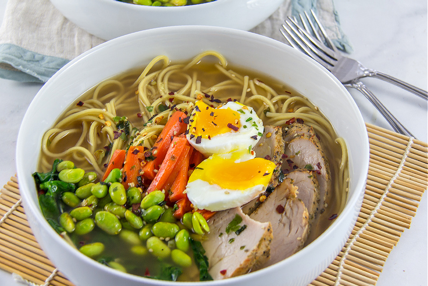 pork edamame and carrot with ramen noodles and egg in a bowl