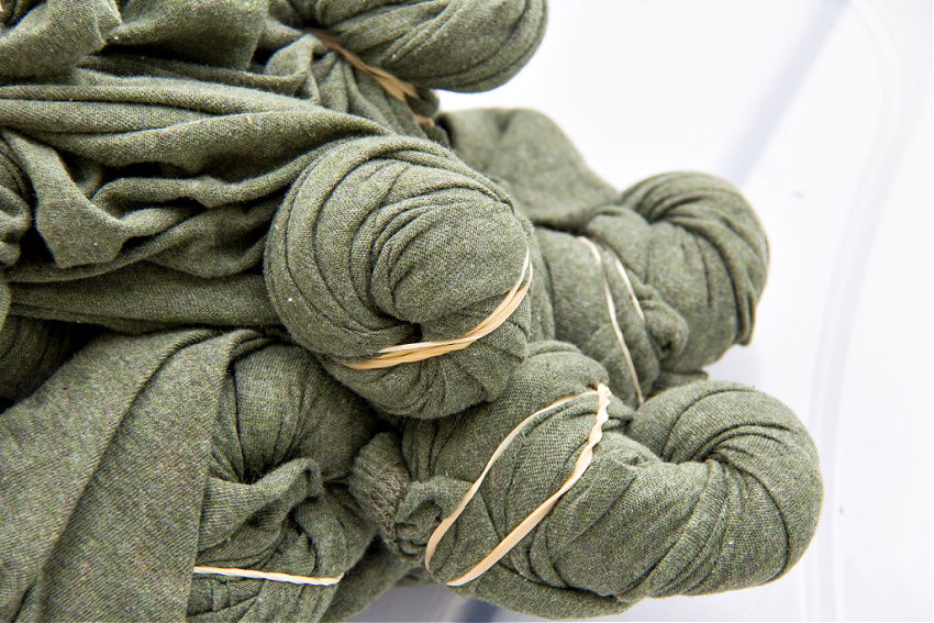 green sheets twisted and tied with rubber bands for dyeing with bleach